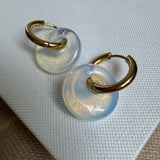 Small gold hoops threaded through a large opaque white disc bead