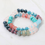 Colorful beaded bracelet in blues and pinks on a white background
