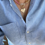 Picture of a woman wearing a layered necklace stack with a bead necklace a  gold link necklace and hammered Heart pendant and small bead necklace.