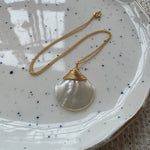Gold necklace with a large freshwater pearl speckled ceramic plate