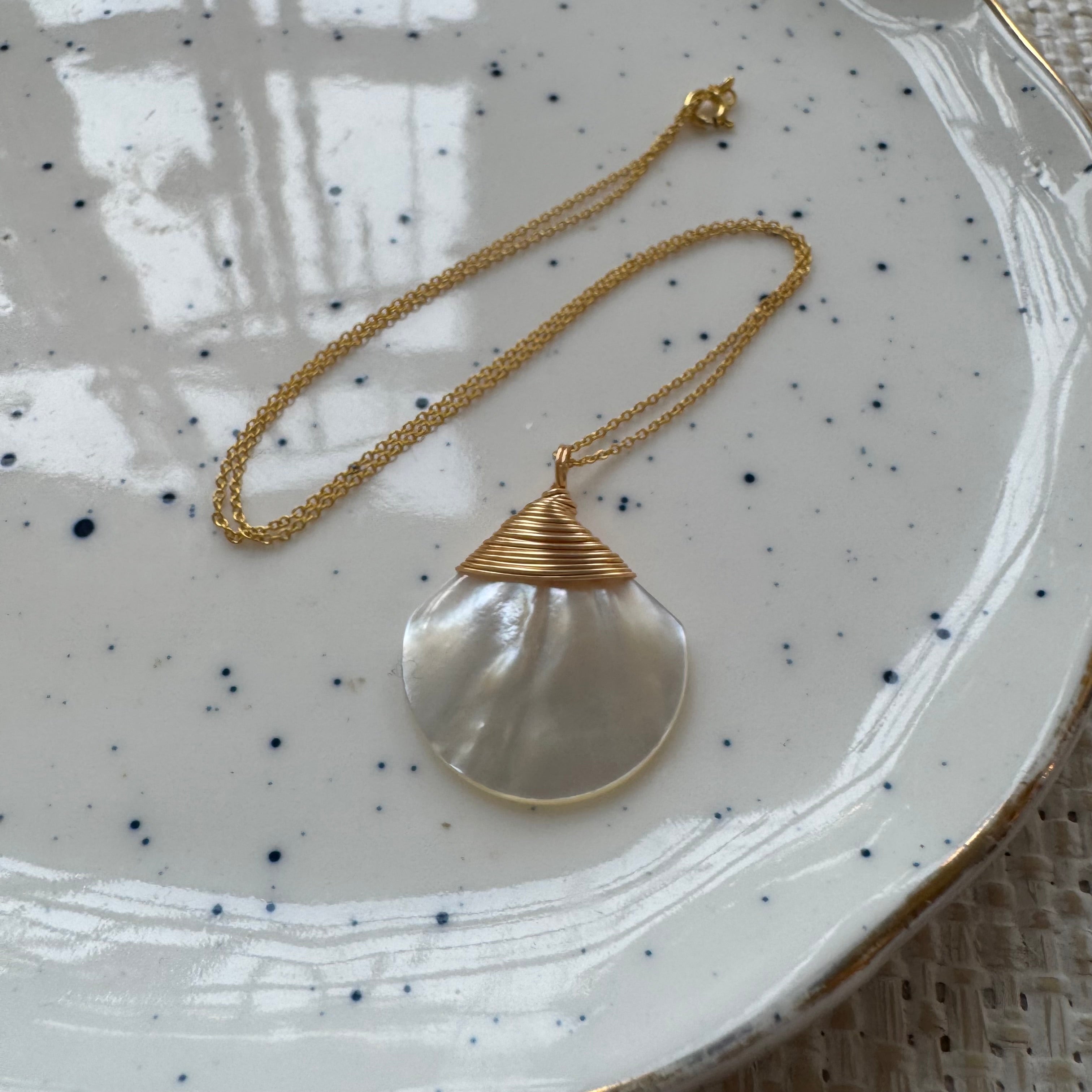 Gold necklace with a large freshwater pearl speckled ceramic plate