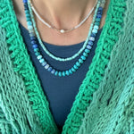 Picture of the front of a woman wearing a set of three bead necklaces. Necklace beads are blues and turquoise