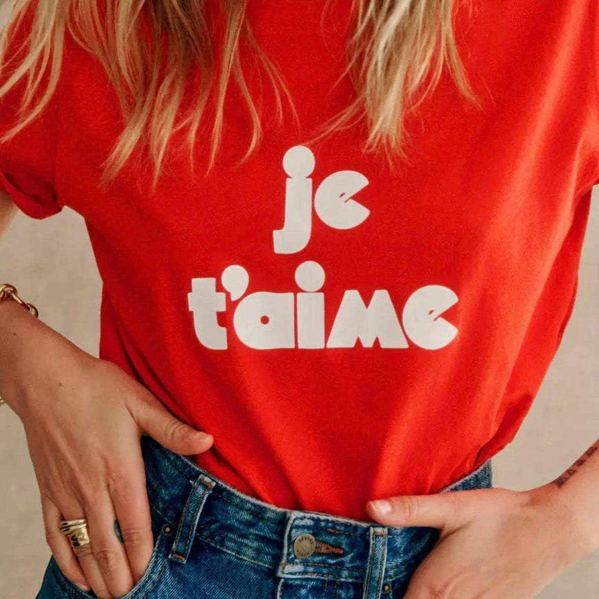 Person wearing a red t-shirt with 'je t'aime' text, standing against a neutral background