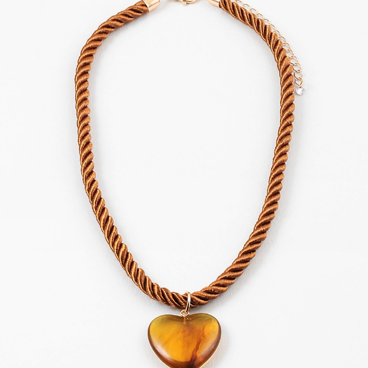 Necklace with a twisted brown cord and heart-shaped amber pendant on a white background