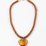 Necklace with a twisted brown cord and heart-shaped amber pendant on a white background