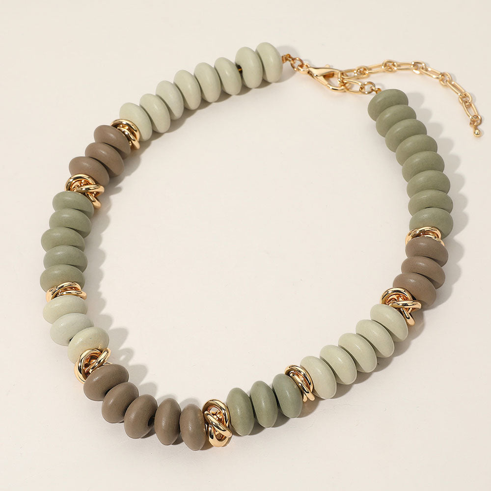 Necklace with green and brown beads and gold accents on a light beige background