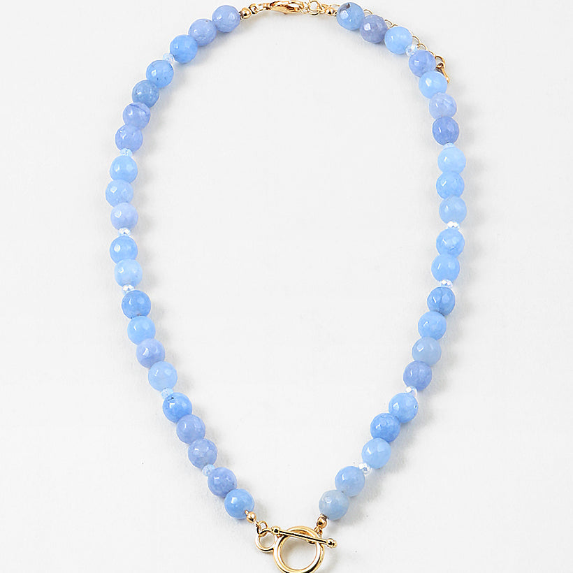 Light blue bead necklace with a large gold toggle clasp at its center.