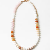 Picture of a beaded necklace in light pink, whites and oranges