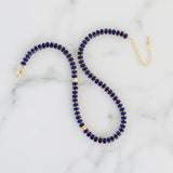 Picture of a necklace with dark blue beads, red spacer beads and gold accent beads