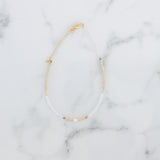 White and gold beads necklace on a marble background.