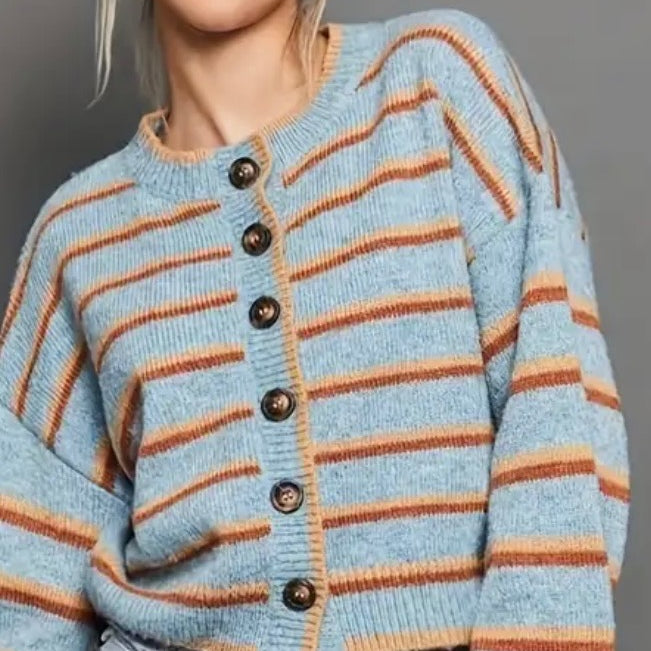 Light blue cardigan with orange and rust colored stripes and black buttons on a gray background