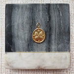 Picture of a gold disc pendant with a butterfly design.