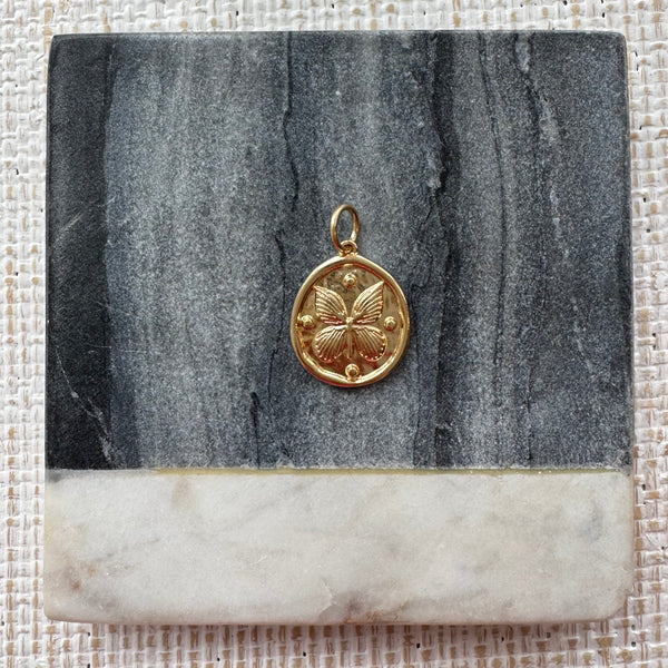 Picture of a gold disc pendant with a butterfly design.