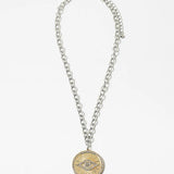 Necklace made of mixed metals with a large disc pendant with an evil eye emblem.