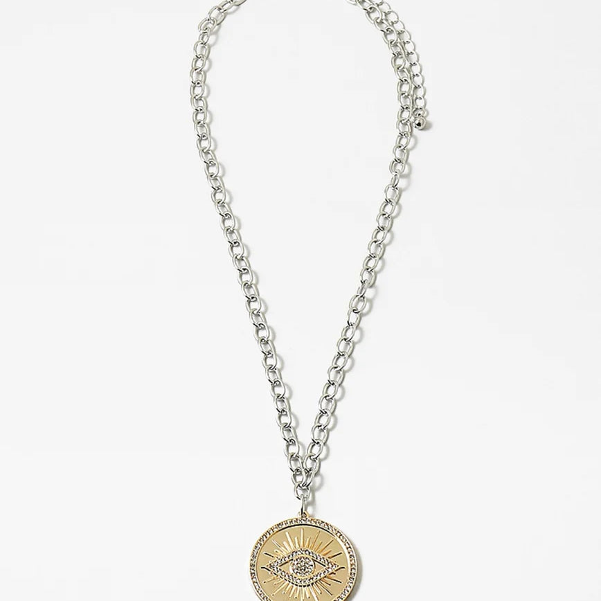 Necklace made of mixed metals with a large disc pendant with an evil eye emblem.