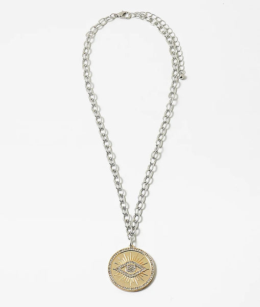 Necklace made of mixed metals with a large disc pendant with an evil eye emblem.