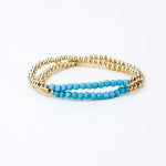 Set of two gold bead bracelets with a section of light blue beads.