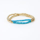 Set of two gold bead bracelets with a section of light blue beads.