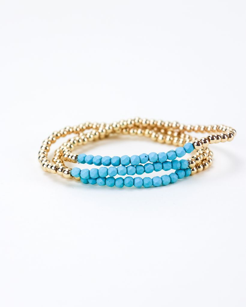 Set of three gold bead bracelets with a section of light blue beads.