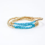 Set of three gold bead bracelets with a section of light blue beads.