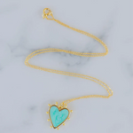 Delicate gold chain with a light blue heart enamel pendant that is edged in gold with small gold beads around its edges.