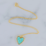 Delicate gold chain with a light blue heart enamel pendant that is edged in gold with small gold beads around its edges.