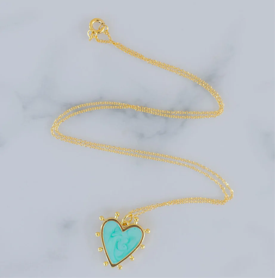 Delicate gold chain with a light blue heart enamel pendant that is edged in gold with small gold beads around its edges.