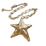 Gold star-shaped pendant on a chain against a white background