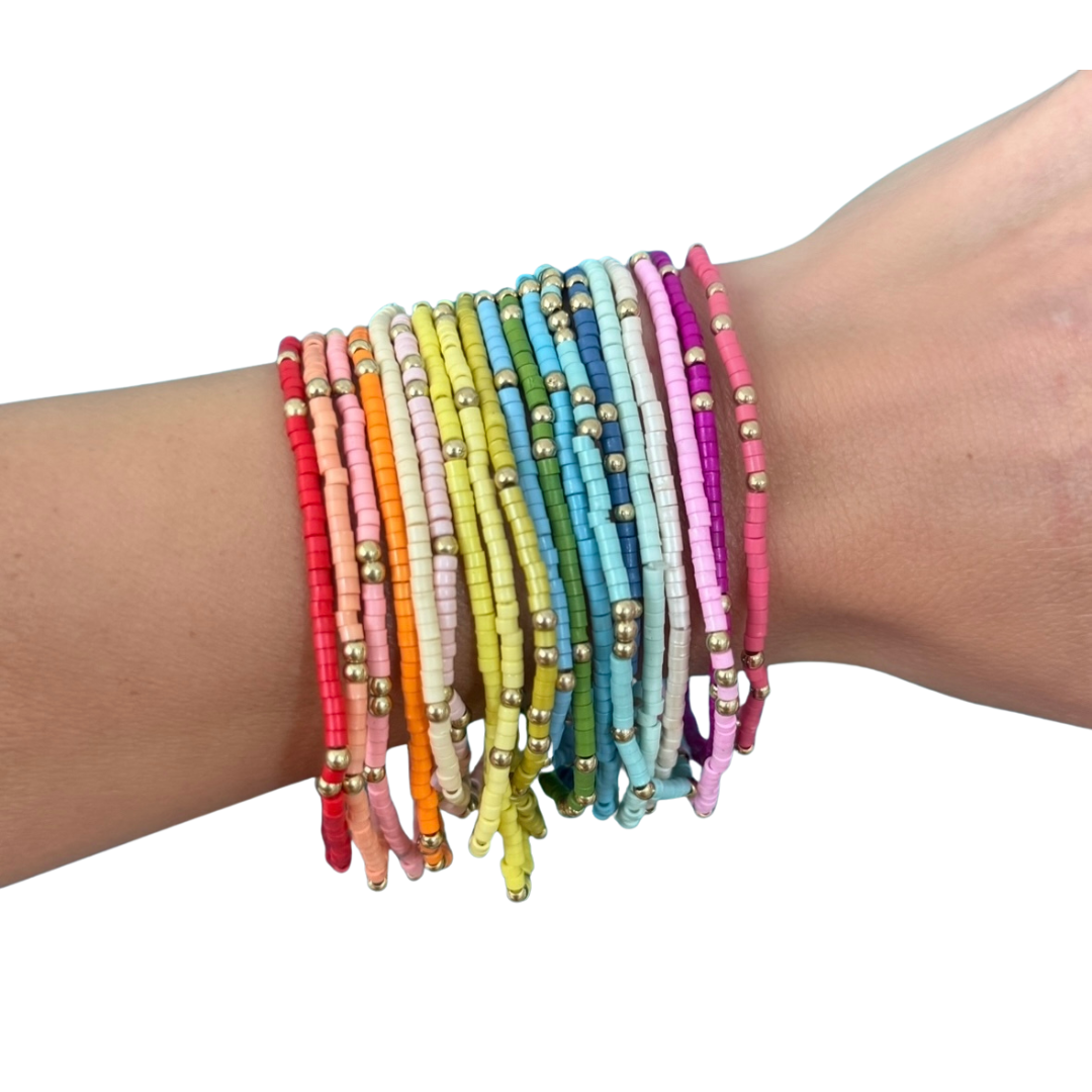 Multicolored beaded bracelets on a wrist against a white background