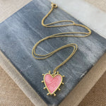 Delicate gold chain with a light pink heart enamel pendant that is edged in gold with small gold beads around its edges.